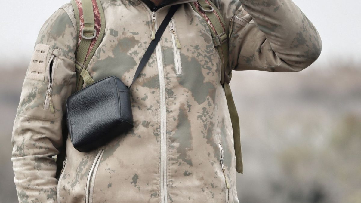 Hunter in a camouflage jacket wearing a chest pouch for carrying optics