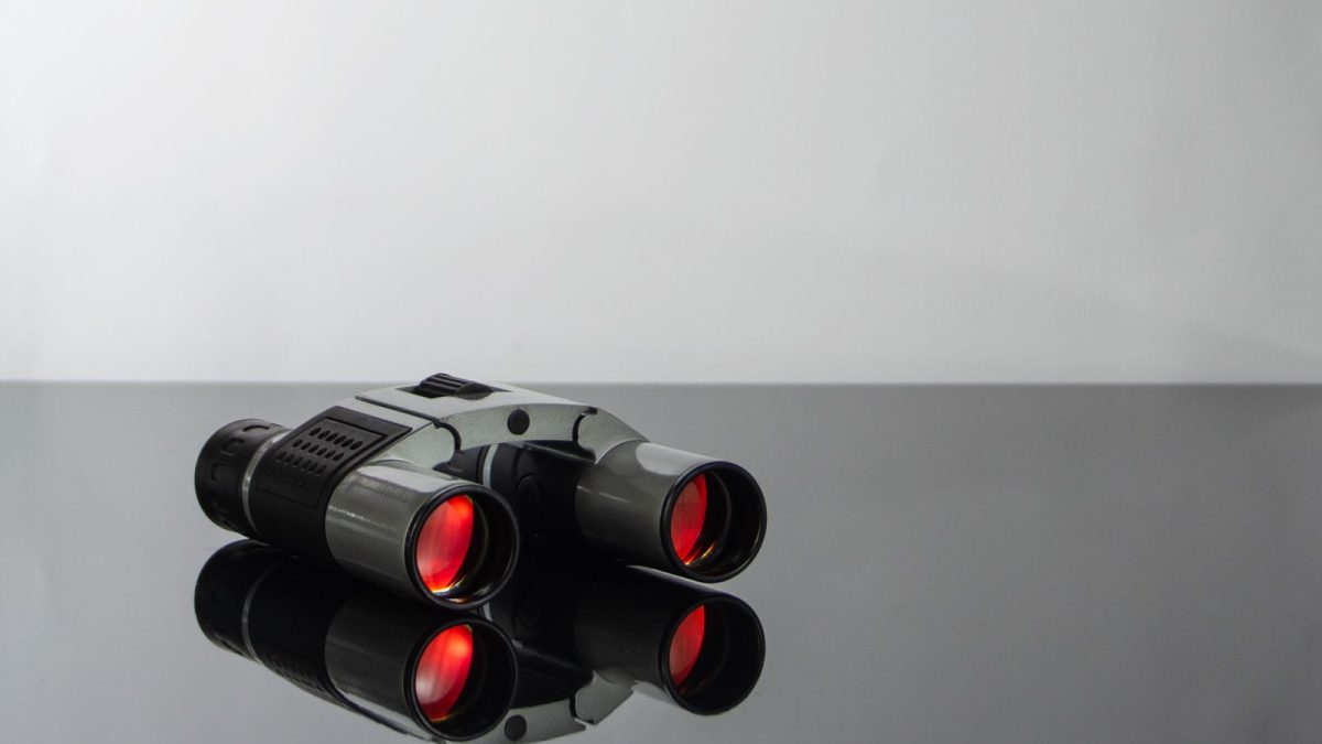 Close-up of binocular objective lenses showing red-tinted coatings